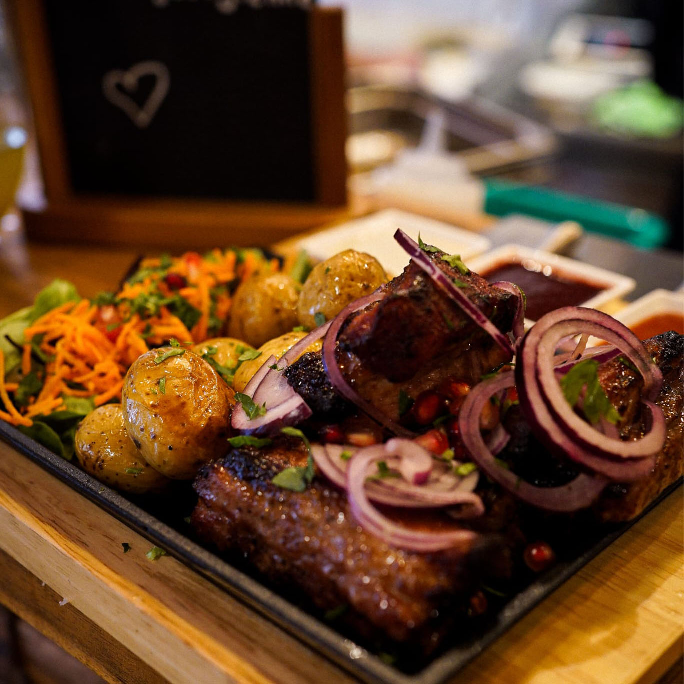 Assiette de viande grillée avec pommes de terre, salade et oignons rouges servie chez ODA